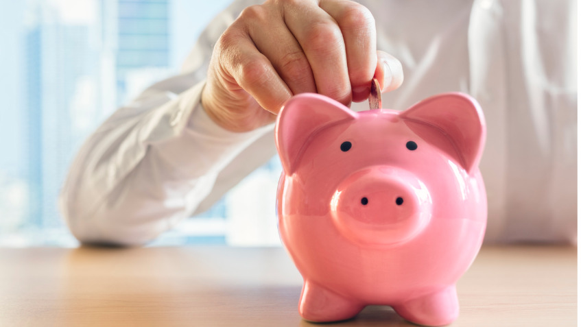 Un homme met une pièce de monnaie dans un cochon-tirelire. Il a fait des économies grâce à ses déductions d’impôts.
